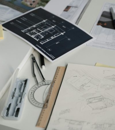 High-angle view of a desk with blueprints, sketches, and architectural tools.