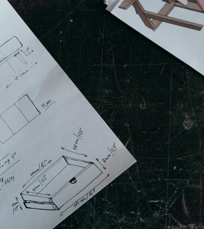 Intricate carpentry design sketches on paper with pens, showcasing furniture project planning.